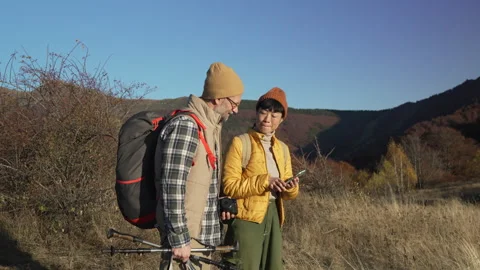 Hiking couple checking smart phone for directions in the mountains Stock Footage 320461161