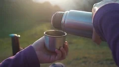 Thermos with a hot drink on mountain waterfall Stock Photo by YouraPechkin