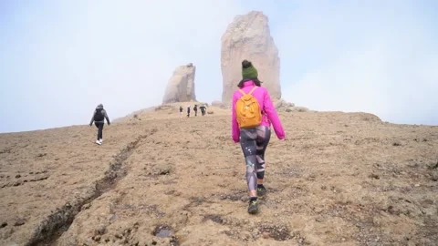 Hiking group ascend to Roque Nublo in a misty morning with fog Stock Footage 231787975
