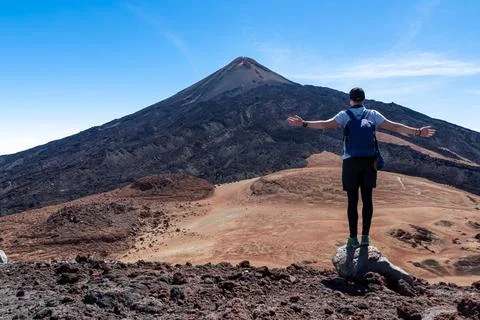 Hiking man with backpack standing on the summit Pico Viejo with scenic view.. Stock Photos