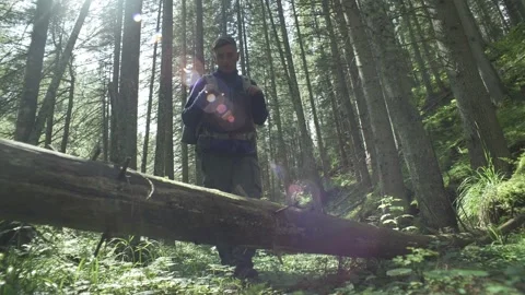 A hiking man in the forest steps over a fallen tree. A guy with a backpack climb Stock Footage 217396276