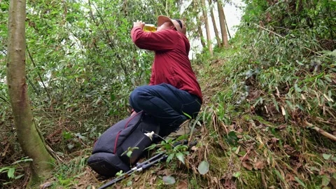 Hiking man  in the primeval forest drinks collected yellow urine to survive. Stock Footage 329547987