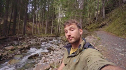 Hiking man tdoing blogging in mountain forest with river Stock Footage 309917548