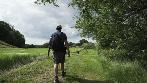 A hiking man walking through a windswept rural scene in the UK Stock Footage 134461373