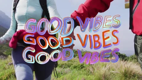 Hiking pair walking hand-in-hand on hillside, GOOD VIBES overlay appearing over Vídeo Stock 333670942