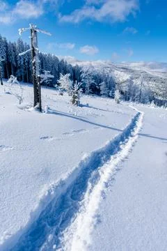 Hiking path through snow in winter mountains landscape under blue sky Stock Photos
