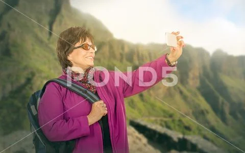 Hiking senior woman photographing highland Stock Photos