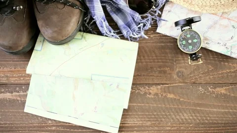 Hiking shoes with topo map and compass on a wood background. Stock Footage