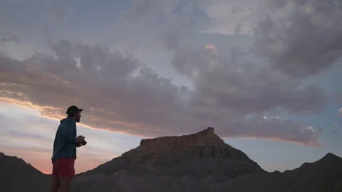 Hiking through the desert while documenting breathtaking cloud formations at Stock Footage 288566776