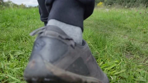 Hiking through the grass, close-up of shoes recorded in slow motion. Video stock 220830276