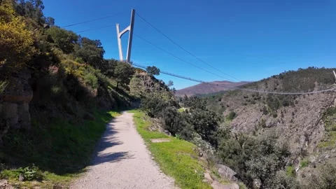 Hiking trail along a deep mountain canyon with a bridge in the background Stockbeeldmateriaal 332368745