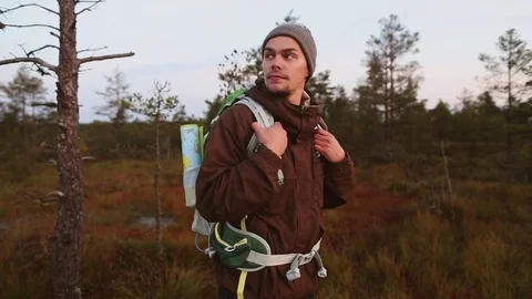 Hiking young man walking through the bogs wooden trail at sunrise Stock Footage 80340288