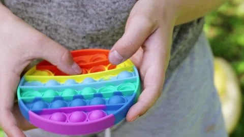 ?hild plays push pop bubble fidget toy outdoors Stock Footage 158842874