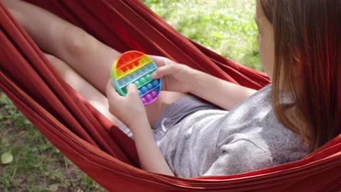 ?hild plays push pop bubble fidget toy outdoors Stock Footage 158842938