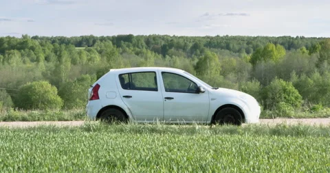 A hill with a rural road on which an empty passenger car is stopped. Vídeos de archivo 276627699