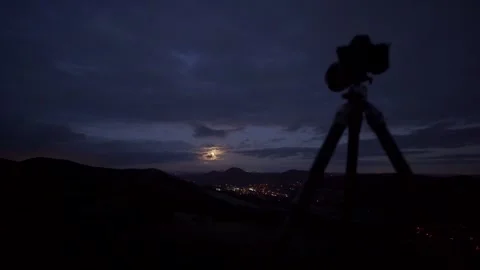 A hill summit view of a town at night with a camera and tripod in view Stock Footage 265028979