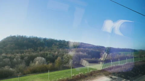 Hills and meadows forests seen through large glass windows of a fast train Video stock 167982265