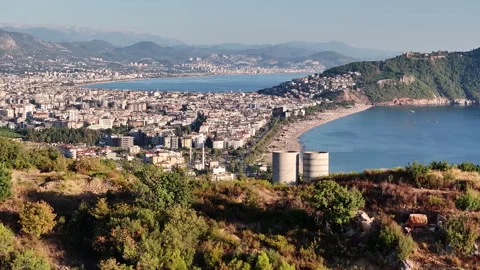 A hillside with greenery, two cylindrical structures, and a cityscape Stock Footage 301627088