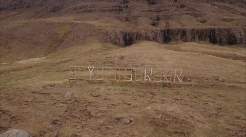 Hillside letter sign below a thin fjord waterfall 動画素材 64877150