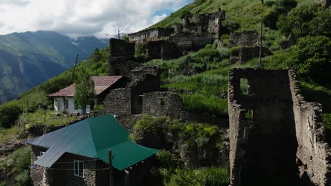 Hillside Ruins and Intact Structures in a Mountain Village with a Verdant Stock Footage 265563593
