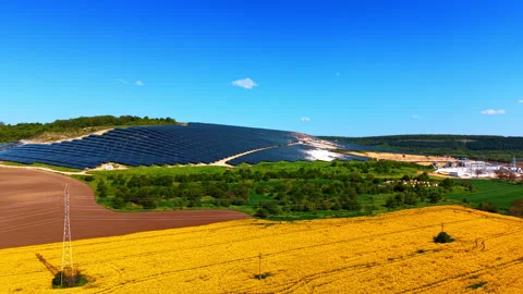 Hillside solar array above blooming rapeseed crop and pylon Stock-Footage 335694862