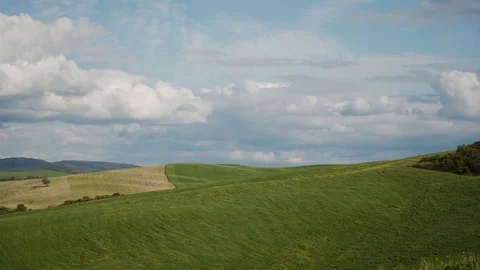 Hilly green meadow with dreamy clouds and blue sky. Tuscan landscape of serenity 库存影片 124181746