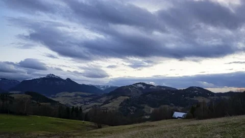 A hilly rural landscape, clouds moving at dusk, grassy meadows with trees Stock Footage 238533147