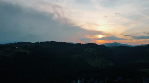 Hilly terrain covered with coniferous trees against sunset cloudy sky Stock Footage 159684488