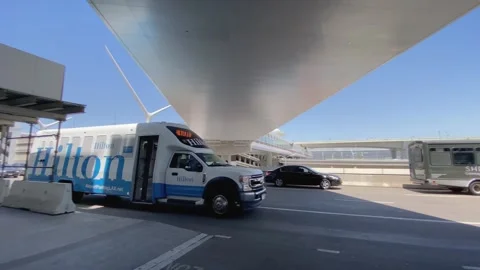 Hilton Hotel shuttle bus driving in LAX airport departures area. Slow motion. Stock Footage 274776931