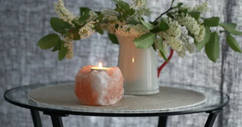 Himalayan salt candle on a table under bird cherry blossom bouquet Stock Footage 132108987