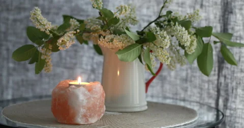 Himalayan salt candle on a table under bird cherry blossom bouquet Stock-Footage 132109024