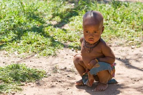 Himba boy sits on the ground. Stock Photos