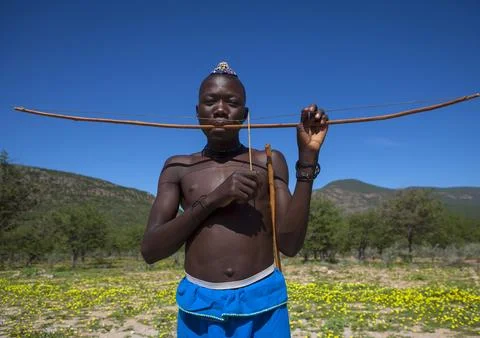 Himba man playing bow instrument, Kunene Region, Epupa, Namibia Stock Photos