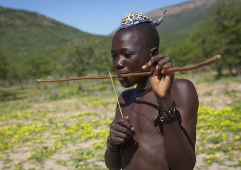 Himba man playing bow instrument, Kunene Region, Epupa, Namibia Stock Photos