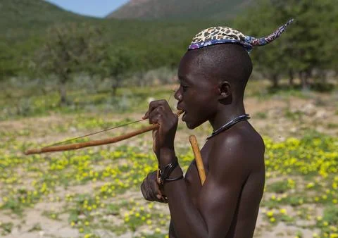 Himba man playing bow instrument, Kunene Region, Epupa, Namibia Stock Photos