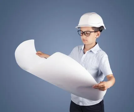 Hindu boy engineer in a hard hat and glasses reads blueprints on a blue Stock Photos