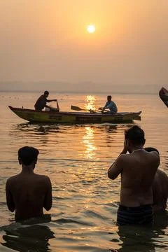 Hindu devotees offering morning prayers in sacred ganges river at dawn Stock Photos