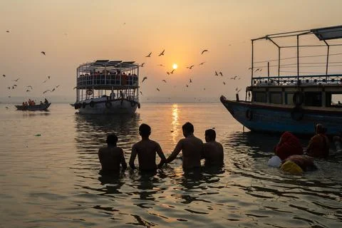 Hindu devotees performing sacred ganges river prayer during calm sunrise at.. Stock Photos