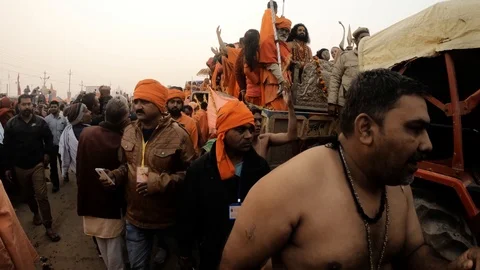 Hindu monks in orange clothes sit and stay on decorated tractor with umbrela and Stock Footage 106444045
