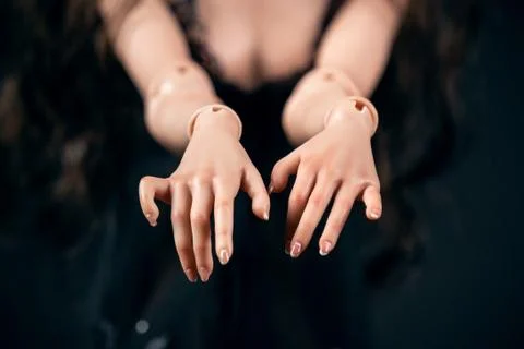 Hinged doll on a black background. Beautiful female hands closeup. Stock Photos