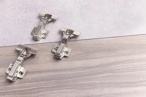 Hinges placed on a wooden surface with a grey background and three hinges i.. Stock Photos