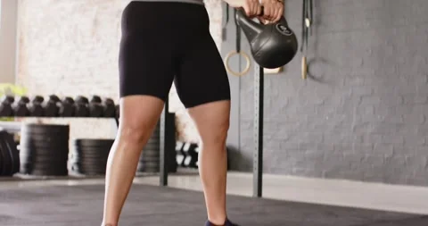 Hip hinge initiating kettlebell swing in gym, woman driving hips forward and Stock Footage 345123608