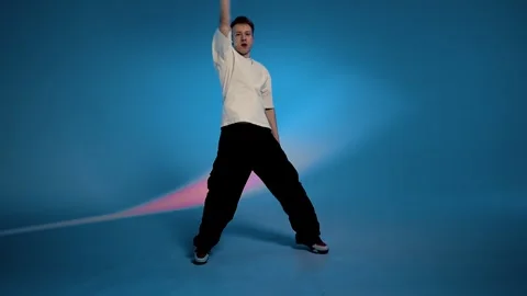 Hip hop dancer performing dynamic step in blue studio Stock Footage 345602487