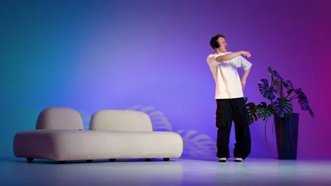 Hip hop dancer performing sharp hand gestures in a colorful studio Stock Footage 345602498