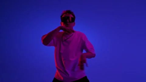 Hip hop dancer posing with raised arm under neon studio lights Stock Footage 345602223