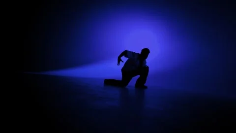 Hip hop dancer striking a dramatic pose under blue studio lights Stock Footage 345601990