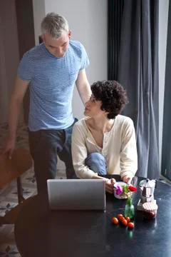 A hip mixed couple using a laptop at the dining table Stock Photos
