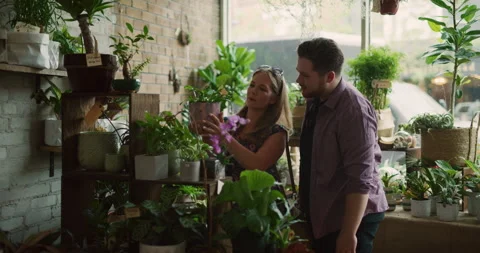 Hip young couple looking at potted plants and flowers in interior boutique plant Stock Footage 199461632