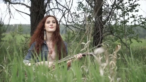 Hippie girl playing guitar on field Stock Footage