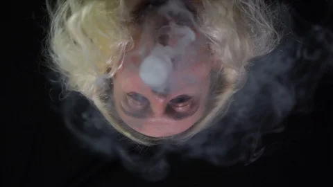 Hippie vaping big ring of steam and sends it to the camera with in slow motion Stock Footage 127389100